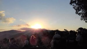 people watching sunrise on a rock