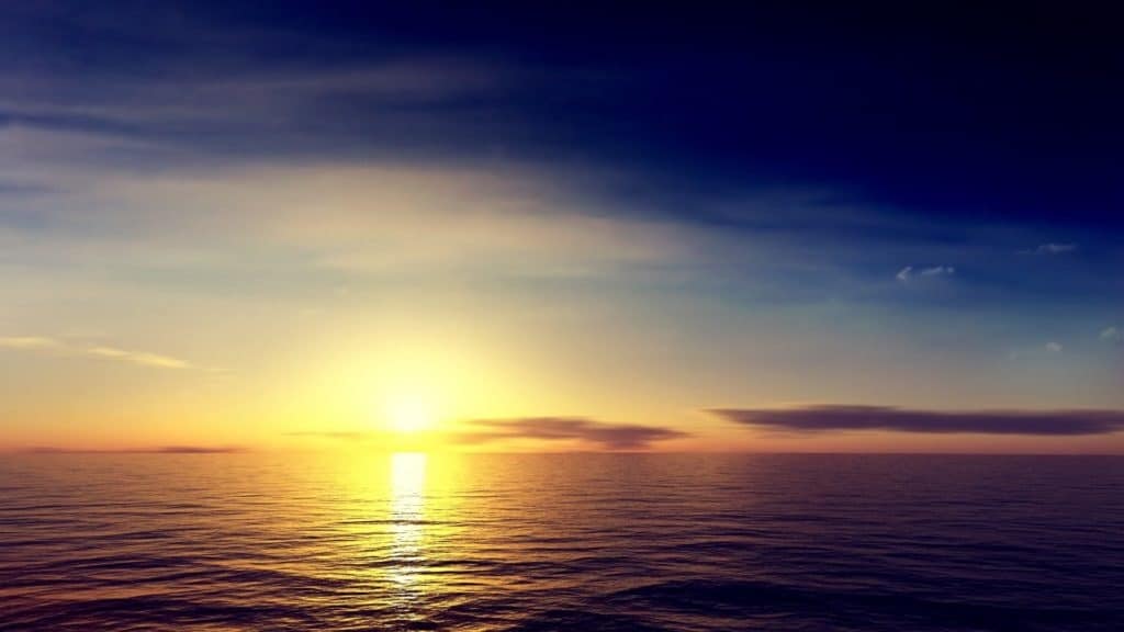 sun rising over calm ocean